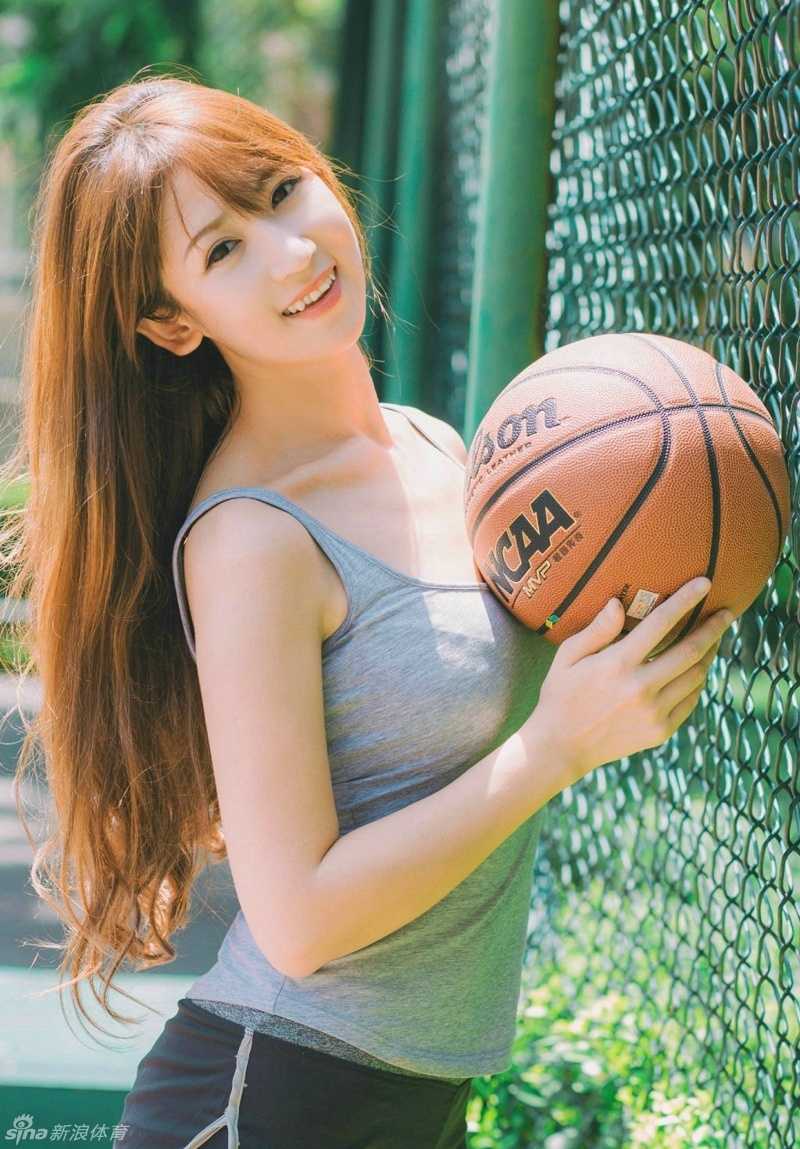 以胸部托举篮球，湿漉漉的长发增添几分性感，球场灯光映照完美侧颜，水珠在锁骨处闪闪发亮