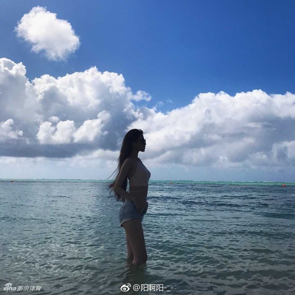 海风吹乱了发丝，马阳阳站在海边的礁石上，一手轻轻按住草帽，眼神望向远方，泳装勾勒出她完美的身形，仿佛一幅定格在夏日里的时尚海报。